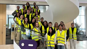 Eine Gruppe junger Menschen mit Warnwesten auf einer Wendeltreppe.