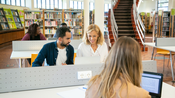 [Translate to English:] Menschen sitzen in einer Bibliothek