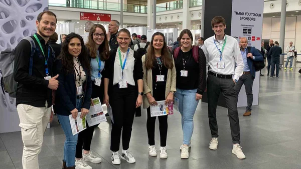 Eine Gruppe von sieben Studierenden in einer Messehalle. 