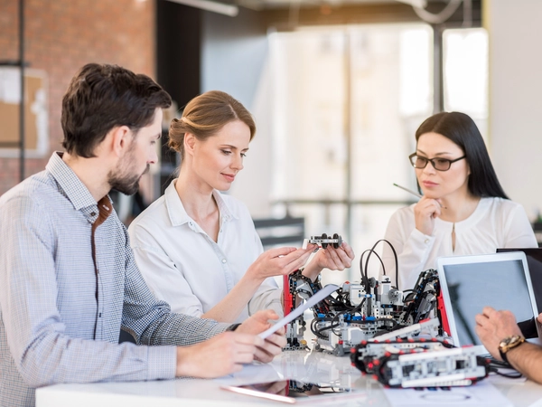 Drei Personen betrachten technische Bauteile 