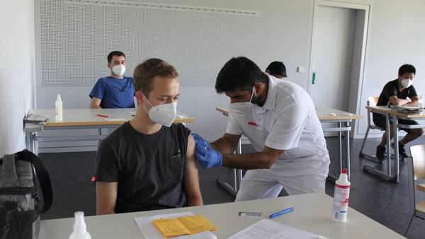 Arzt impft Studenten gegen Covid-19.