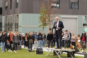 Präsident Walter Schober steht vor rund Studierenden auf der Campuswiese.