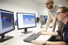 Two employees are sitting in front of a PC.